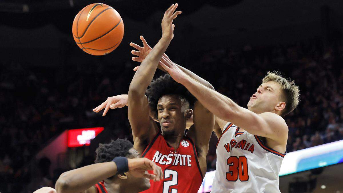 N.C. State's Musa Sagnia and Paul McNeil Jr. battle for a rebound with Virginia's Dallin Hall during the second half of the Wolfpack’s 90-61 loss on Thursday, Feb. 24, 2026, at John Paul Jones Arena in Charlottesville, Va.