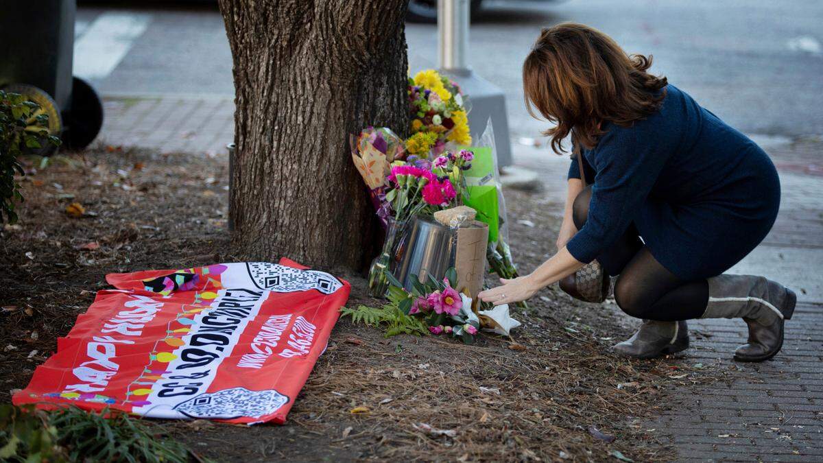 Tonya Mills reaches out to gently touch the memorial for a young girl killed by an out-of-control truck Saturday in the Raleigh Christmas Parade. The girl was a member of the C & C Dance troupe and a their banner from the parade is is on the ground at the memorial Mills’ son was marching in the parade just ahead of the dance troupe.