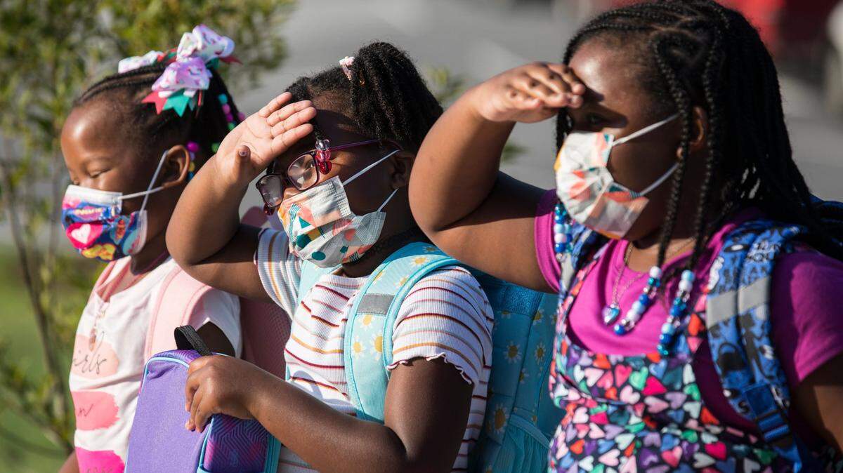 The Robbins sisters, Jessyca, 6, left, Julianna, 6, middle, and Journi, 9, right, pose for pictures for their parents before going into Conn Elementary School in Raleigh, N.C. on the first day of school, Monday, Aug. 23, 2021.