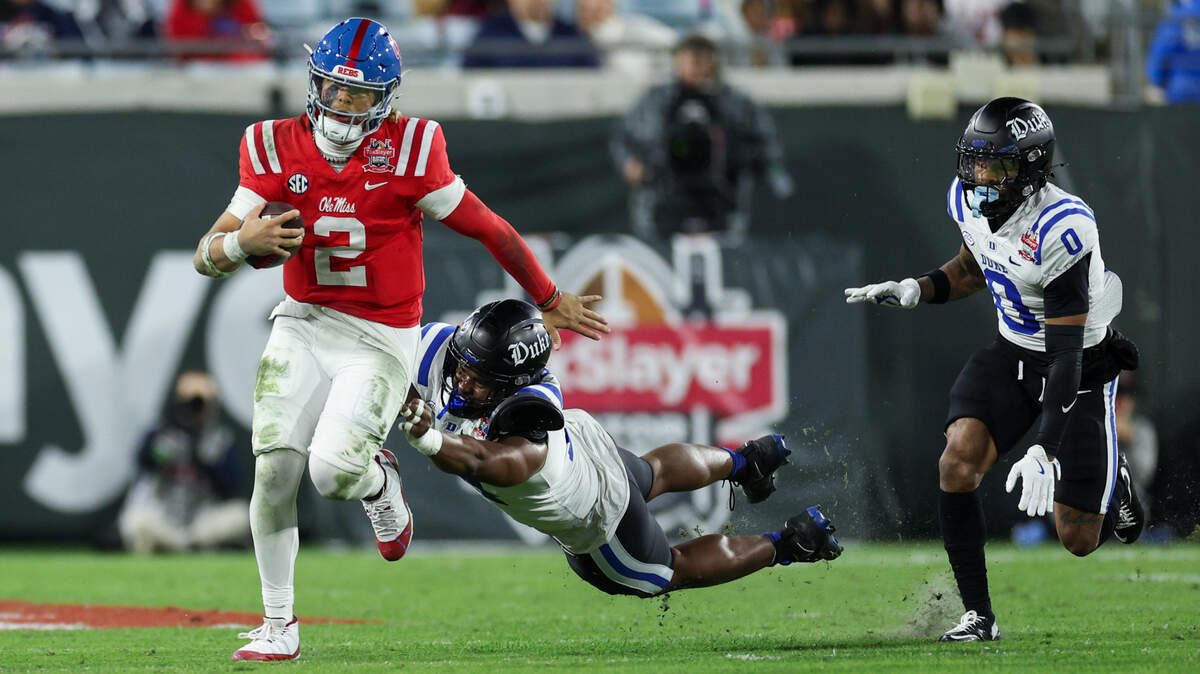 Mississippi Rebels quarterback Jaxson Dart (2) runs with the ball chased by Duke Blue Devils defensive end Michael Reese (14) in the second quarter during the Gator Bowl at EverBank Stadium.