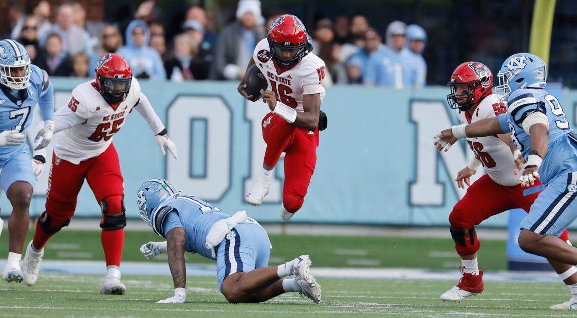 N.C. State quarterback CJ Bailey (16) jumps over North Carolina linebacker Amare Campbell (17) during the first half of N.C. State’s game against UNC at Kenan Stadium in Chapel Hill, N.C., Saturday, Nov. 30, 2024.