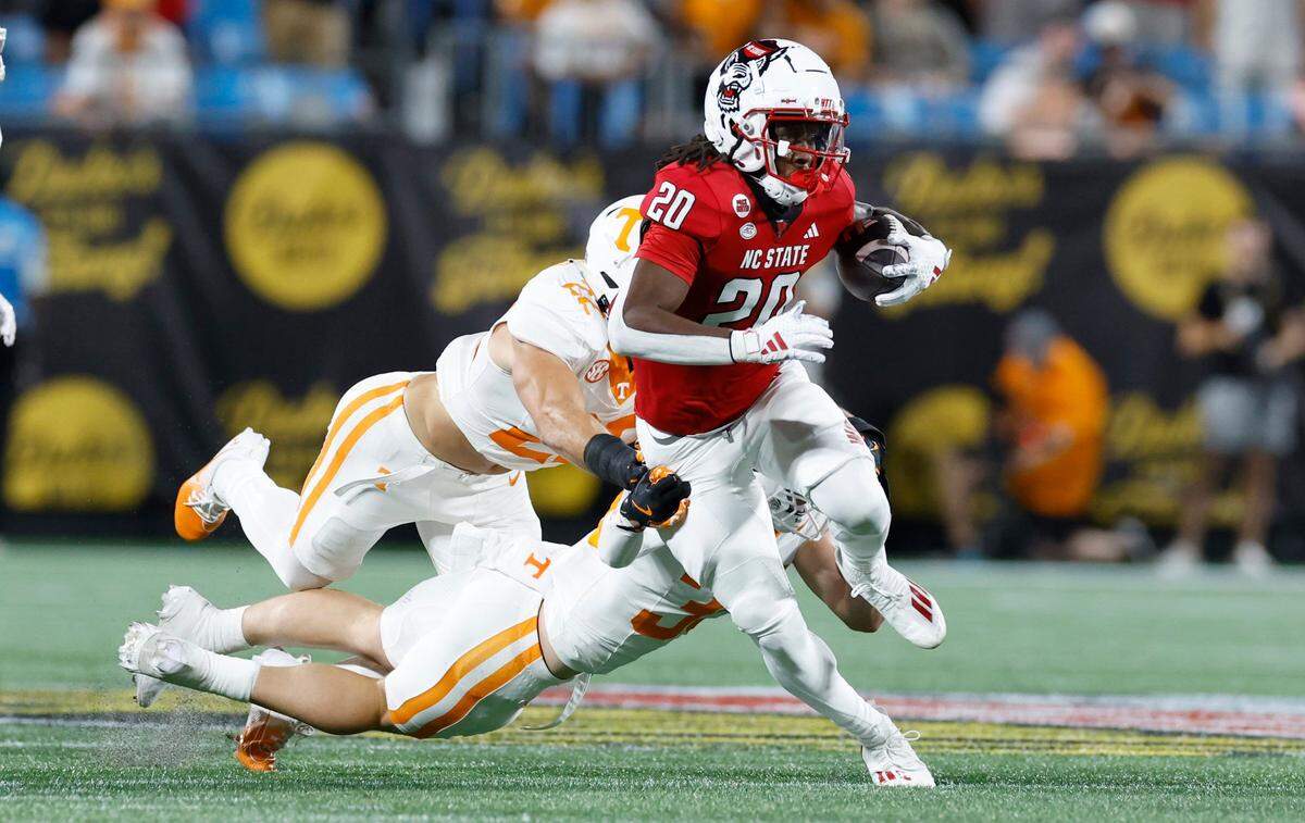 N.C. State running back Hollywood Smothers (20) beats a tackle attempt by Tennessee linebacker Jeremiah Telander (22) and defensive back Will Brooks (35) during the first half of N.C. State’s game against Tennessee in the Duke’s Mayo Classic at Bank of America Stadium in Charlotte, N.C., Saturday, Sept. 7, 2024.