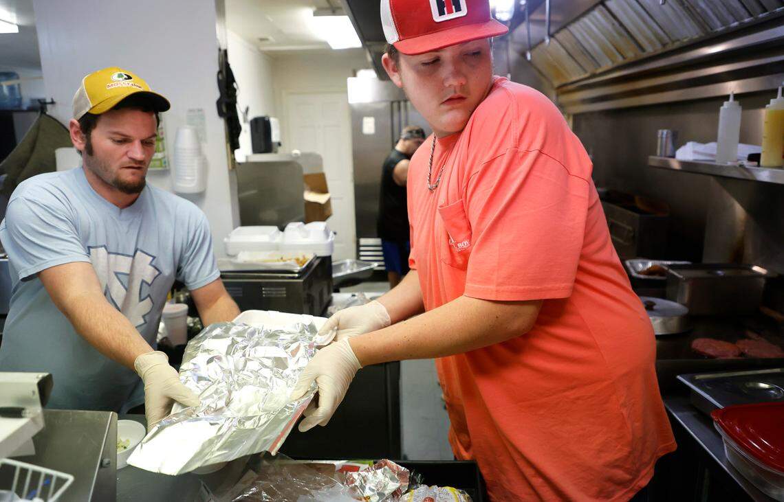 Tyler Hardy, left, and Peyton Jordan work on preparing an order during the lunch rush at Stubbs & Son BBQ in Carthage, N.C., Wednesday, Dec. 7, 2022. The restaurant got its power back Tuesday morning and has been extra busy as people look for meals and ‘people missed us’ said manager Gary Talley.