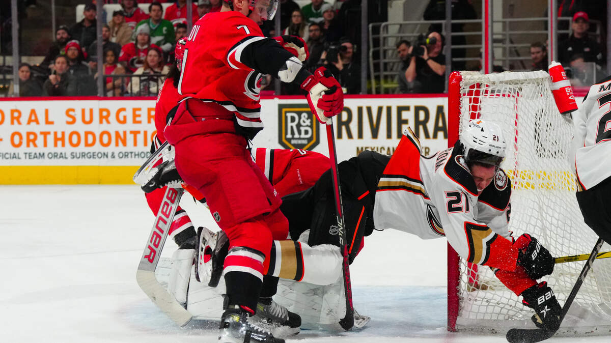 Jan 11, 2024; Raleigh, North Carolina, USA; Anaheim Ducks center Isac Lundestrom (21) is checked into Carolina Hurricanes goaltender Pyotr Kochetkov (52) by defenseman Dmitry Orlov (7) during the second period t PNC Arena. Mandatory Credit: James Guillory-USA TODAY Sports