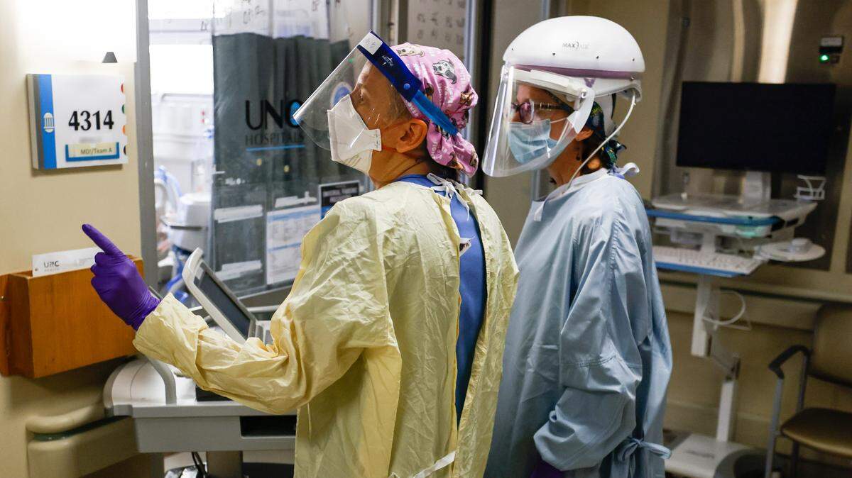Nurses in the Medical Intensive Care Unit consult before entering the room of a COVID patient at UNC Hospital in Chapel Hill, N.C. Wednesday, Aug. 11, 2021.