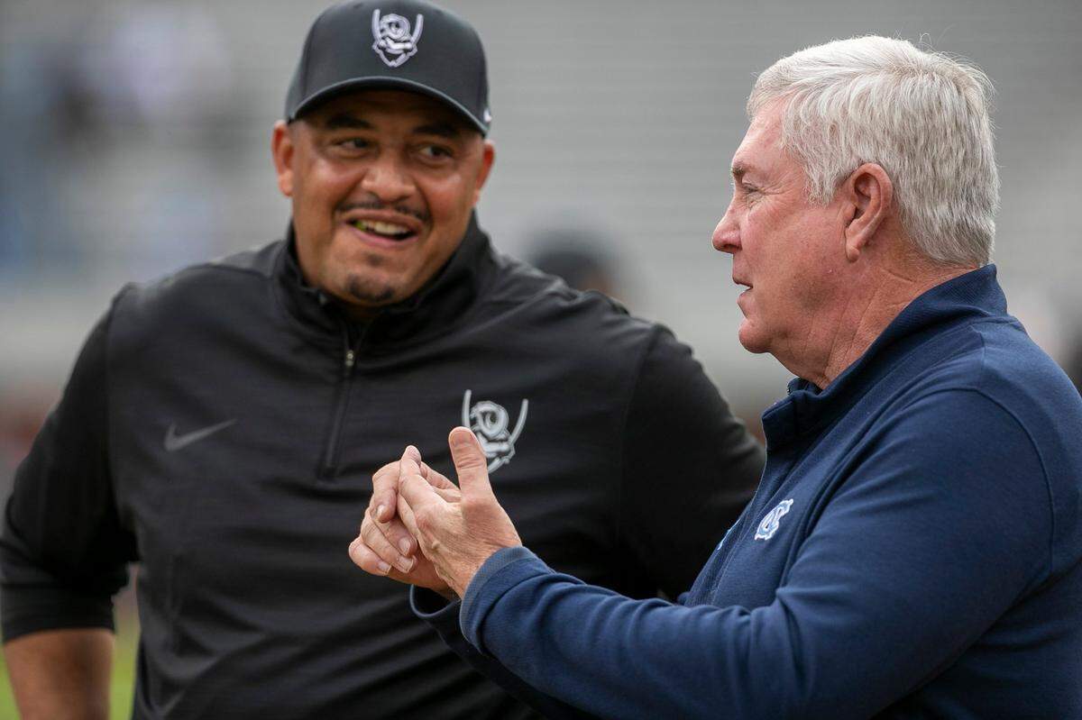 Virginia coach Tony Elliott talks with North Carolina coach Mack Brown prior to their game on Saturday, November 5, 2022 at Scott Stadium in Charlottesville, Va.