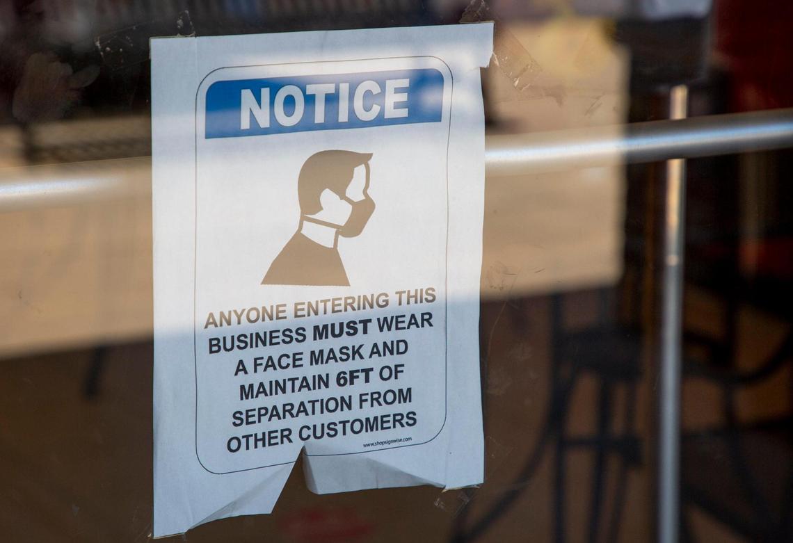 A sign requiring masks is displayed on the front door of Alpha Dawgs, owned by Hisine McNeill who now requires customers who don’t wear a mask to instead show their vaccine card, on Wednesday, May 19, 2021, in Raleigh, N.C.