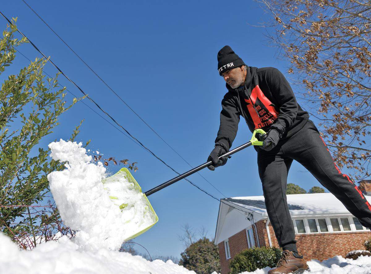 Karthik Sundaramoorthy shovels snow from his driveway on Sunday, Feb. 1, 2026, in Durham, N.C.