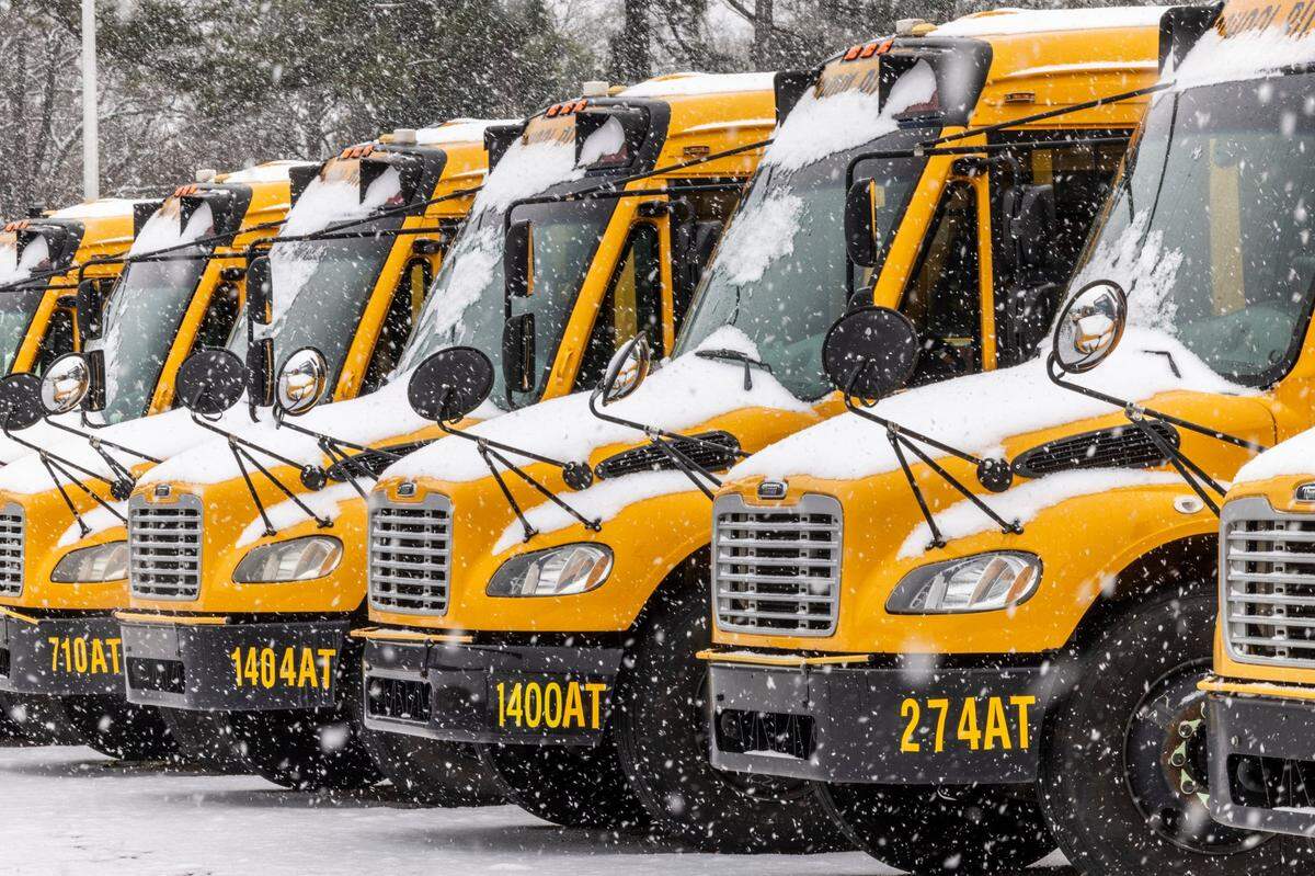 Snow falls on Wake County Public School busses parked on Capital Boulevard in Raleigh on Thursday, Feb. 20, 2025.