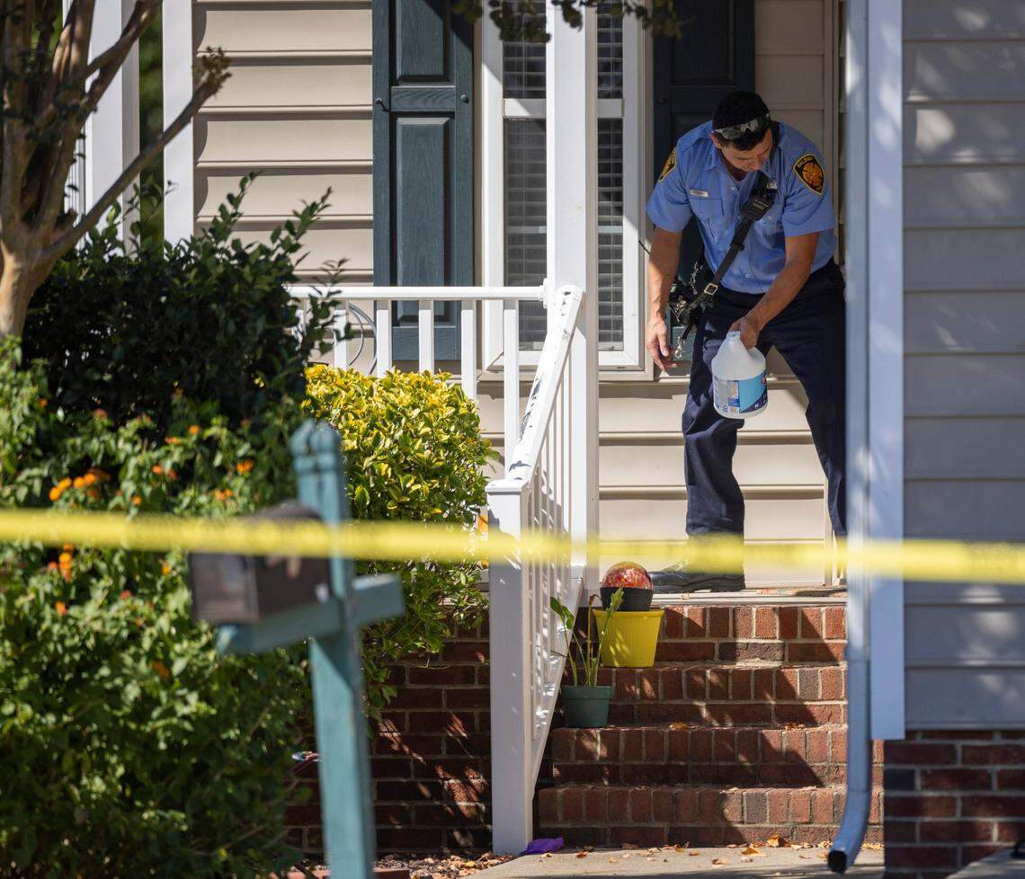 A Raleigh firefighter cleans the porch at 5355 Sahalee Way on Friday, October 14, 2022 in Raleigh, N.C., after the killing of five people yesterday in the Hedingham neighborhood including an off-duty police officer.