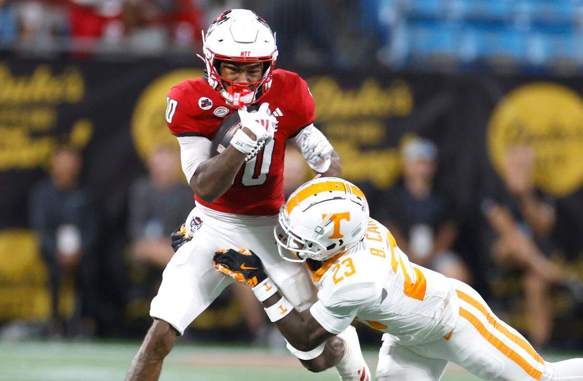 N.C. State wide receiver KC Concepcion (10) gains yards after a reception as Tennessee defensive back Boo Carter (23) tries to tackle him during the first half of N.C. State’s game against Tennessee in the Duke’s Mayo Classic at Bank of America Stadium in Charlotte, N.C., Saturday, Sept. 7, 2024.