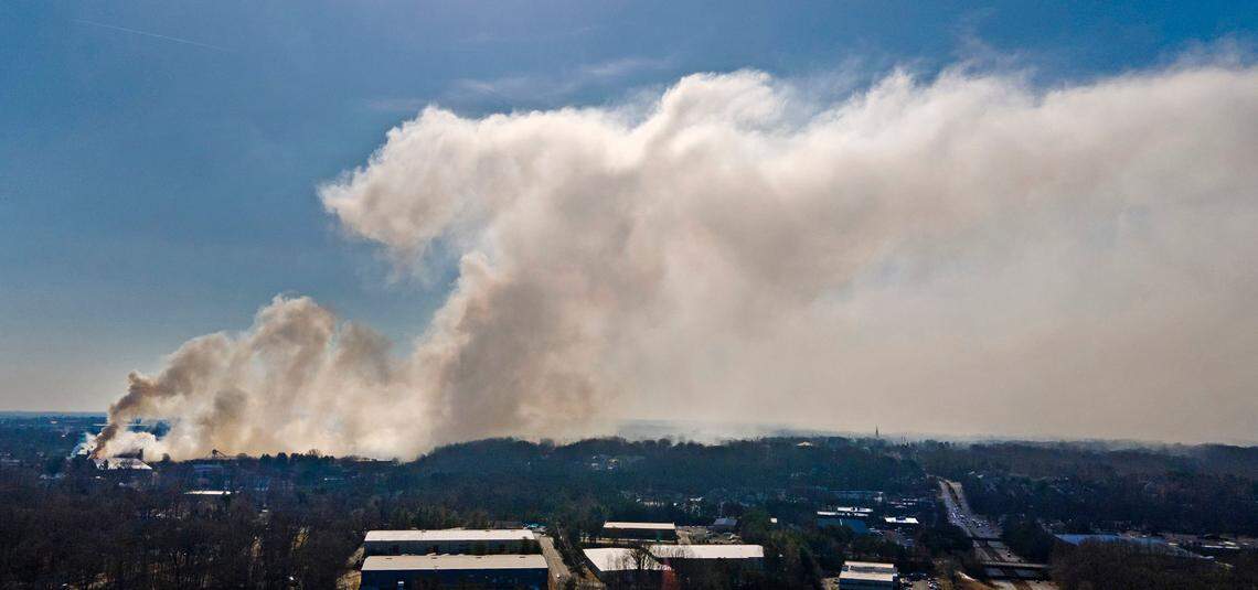 A plume of smoke from the Winston Weaver Co. fertilizer fire drifts west, Tuesday, Feb. 1, 2022, as seen from a drone near University Parkway in Winston-Salem, N.C. , north of the fire. The uncontrolled fire at the fertilizer plant has forced thousands of people to evacuate. Firefighters warn that chemicals at the site near Wake Forest University could cause a large explosion. Authorities urged people within a mile of the site to take shelter elsewhere. No injuries have been reported since the fire started Monday night, but officials say a huge explosion could still happen through Wednesday.