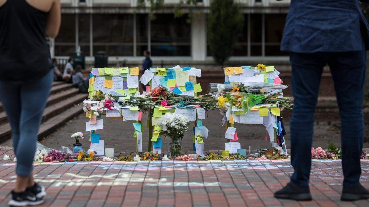 People stand silently at a decorated memorial for UNC-Chapel Hill students reportedly lost to suicide in Chapel Hill, N.C. in 2021.