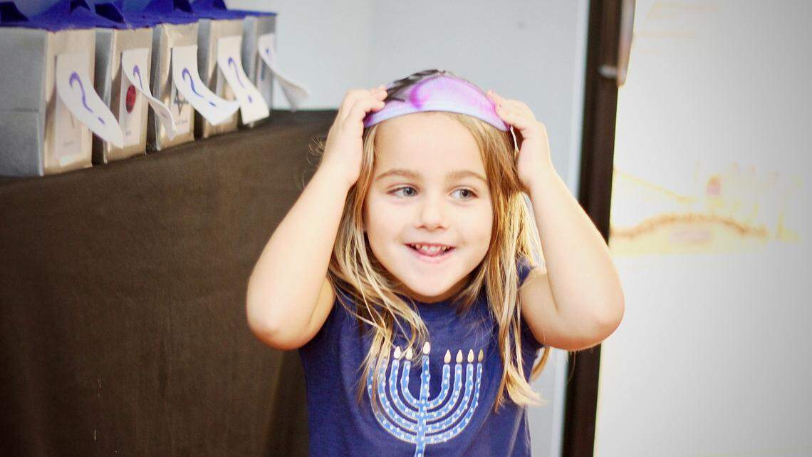 A Durham kindergartener shows off her festive shirt and kippah at Jewish for Good’s 2019 Hanukkah Festival