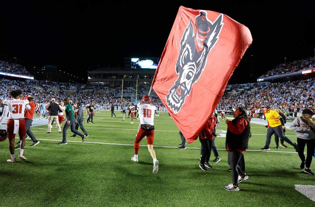 N.C. State quarterback Ben Finley (10) celebrates with the Wolfpack flag after N.C. State’s 30-27 overtime victory over UNC at Kenan Stadium in Chapel Hill, N.C., Friday, Nov. 25, 2022.