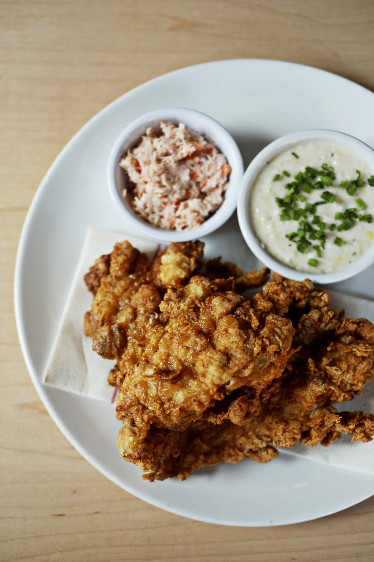 The fried chicken entree at SadieÕs Southern in Chapel Hill is made with a buttermilk brine and a crackly crust that shatters when you bite through it into the juicy meat beneath. It is served here with grits and cole slaw.