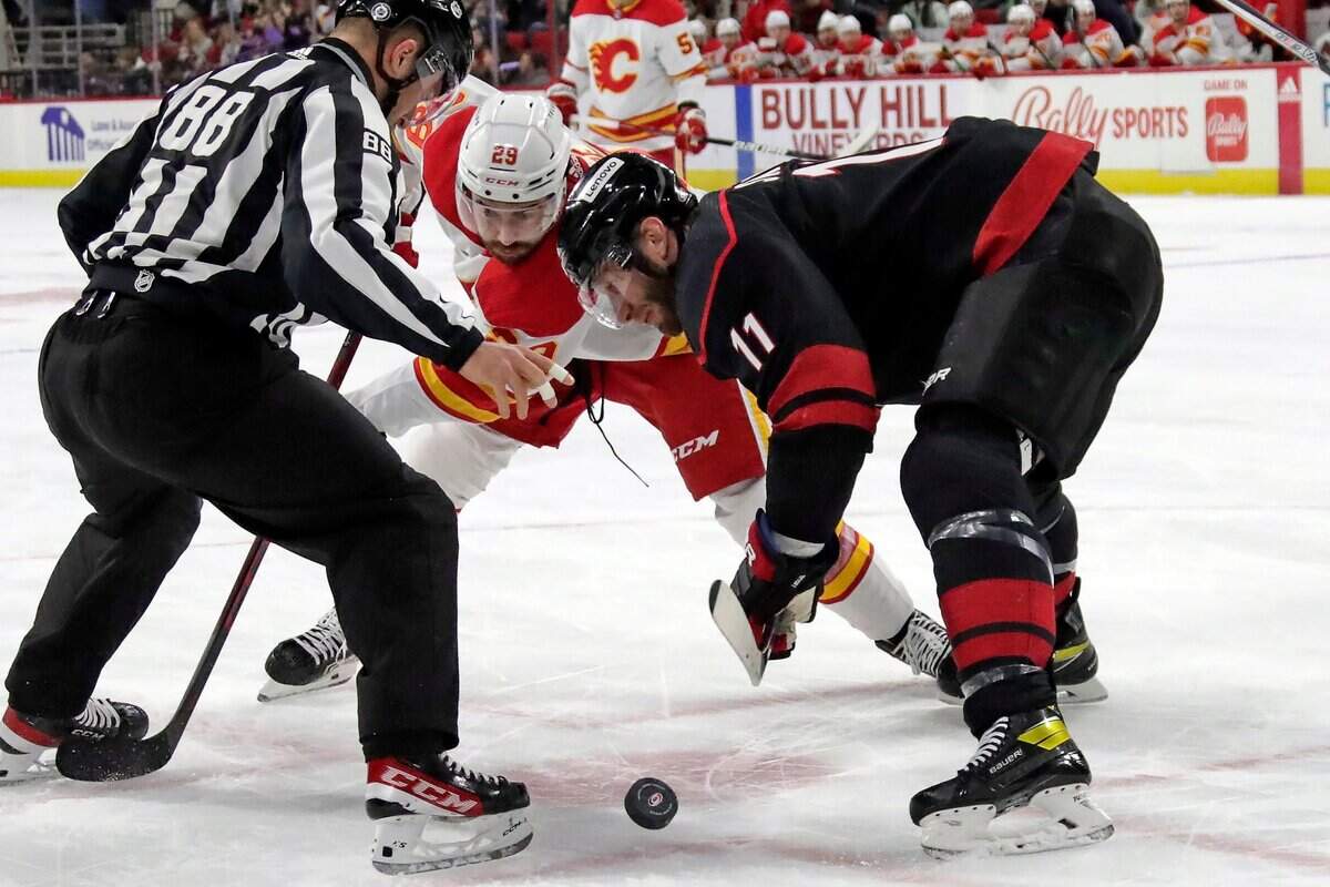 Calgary Flames center Dillon Dube (29) and Carolina Hurricanes center Jordan Staal (11) face off during an NHL hockey game Friday, Jan. 7, 2022, in Raleigh, N.C. (AP Photo/Chris Seward)