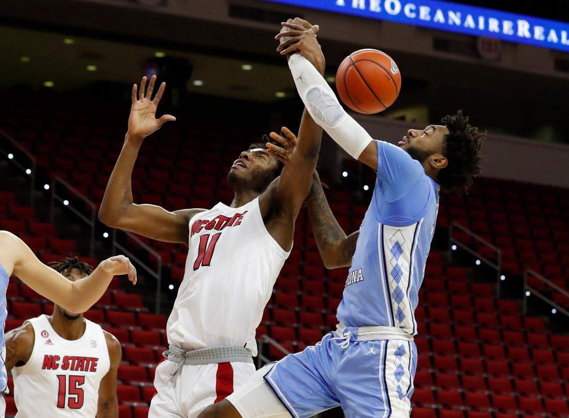 N.C. State’s Jaylon Gibson (11) and North Carolina’s Leaky Black (1) fight for a rebound during the first half of N.C. State’s game against UNC at PNC Arena in Raleigh, N.C., Tuesday, December 22, 2020.