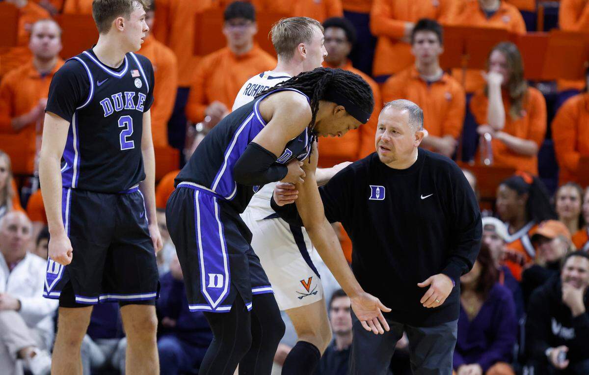 Duke athletic trainer Jose Fonseca checks on Maliq Brown (6) after he was injured during the first half of Duke’s game against Virginia at John Paul Jones Arena in Charlottesville, Va., Monday, Feb. 17, 2025.