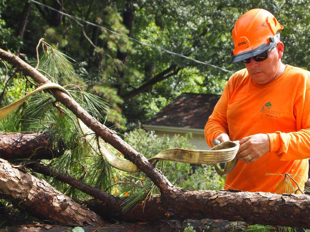 Elmer Perez unties a bundle of limbs dropped in the street by a crane as his tree crew cleans up after Hurricane Florence on Monday, Sept. 17, 2018.