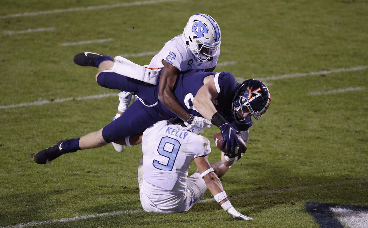 Virginia tight end fights through the defense of UNC’s Don Chapman (2) and Cam’Ron Kelly (9) to score in the third quarter Saturday night, Oct. 31, 2020.