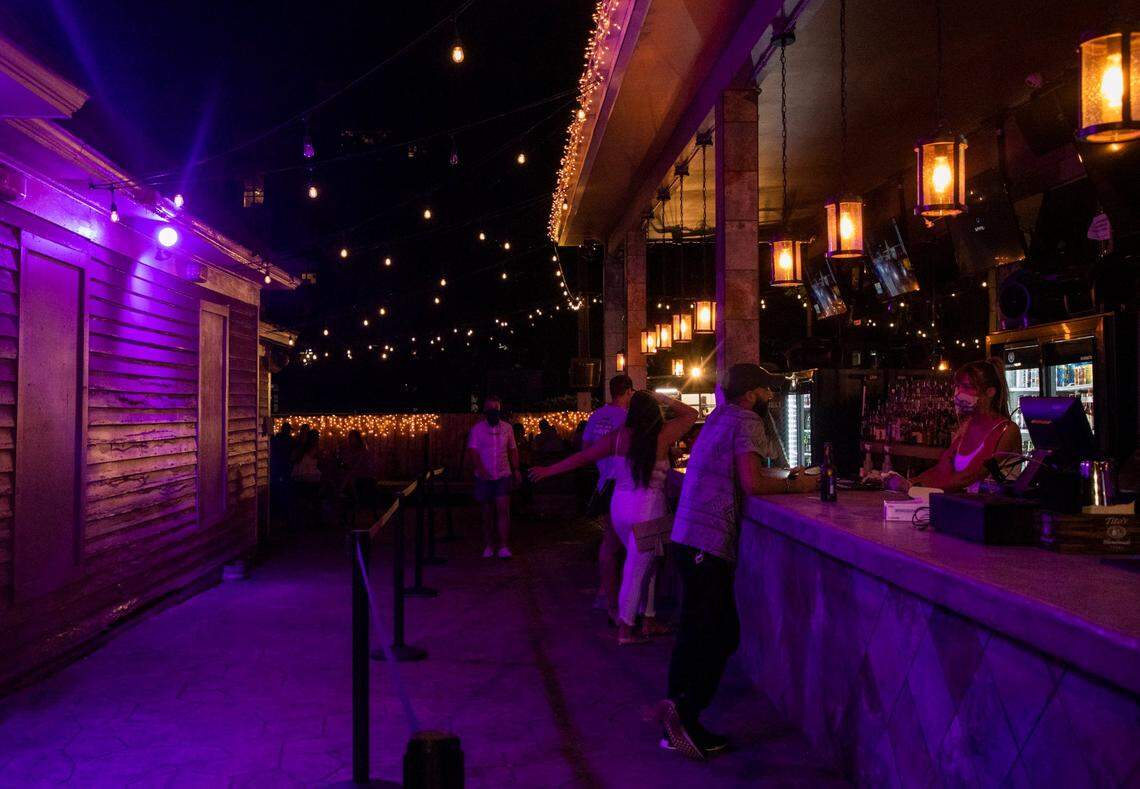 Kenny Czigler, center, talks with Courtney Bray, right, a bartender at the Cornerstone Tavern on Glenwood Avenue, on Friday, June 26. Starting Oct. 2, North carolina bars can open outdoors only at 30% of outdoor capacity, or 100 guests, whichever is less.