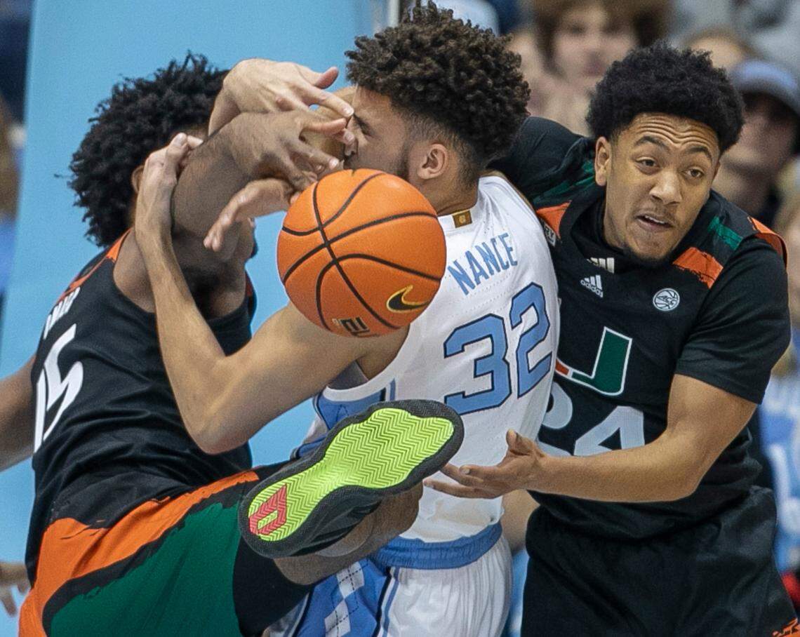 Miami’s Norchad Omier (15) and Nijel Pack (24) tie up North Carolina’s Pete Nance (32) in a battle for a rebound in the first half on Monday, February 13, 2023 at the Smith Center in Chapel Hill, N.C.