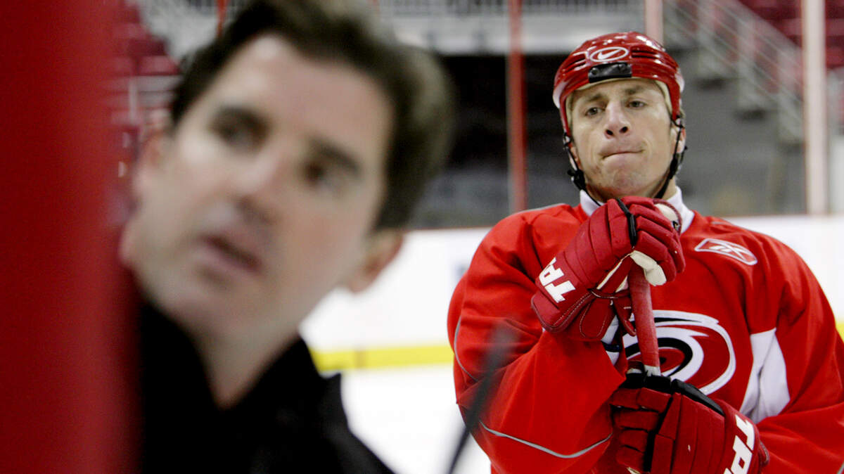 A 2006 photo shows Canes captain Rod Brind’Amour, right, looking on as head coach Peter Laviolette diagrams a play during practice.