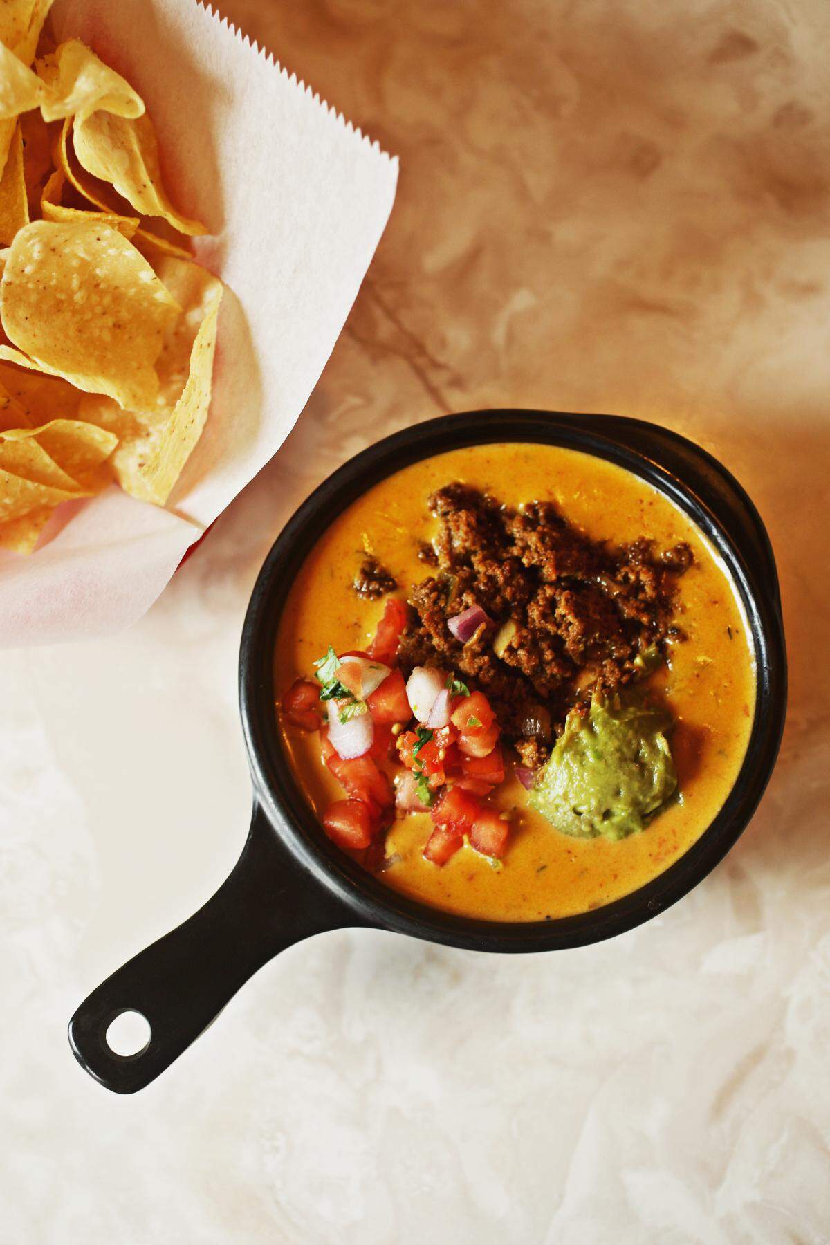 Chuy’s queso compuesto is a generous bowl of warm chile con queso topped with dollops of seasoned ground sirloin, guacamole, and pico de gallo.