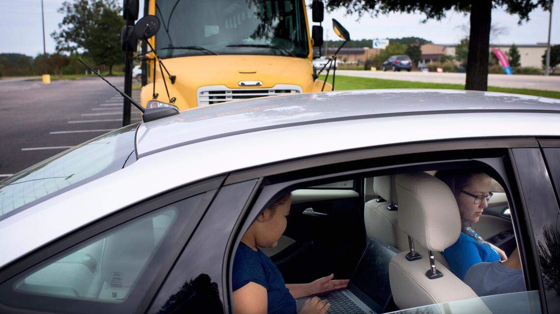 Students do online schoolwork using a “WiFi Bus” parked at a grocery store lot in Lumberton, N.C., Oct. 28, 2020. Millions of American students are grappling with the challenge of learning remotely without adequate home internet service, particularly in poorer locales like Robeson County.