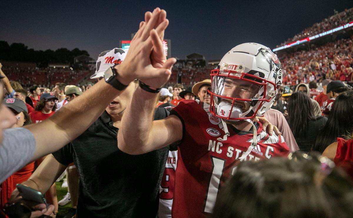 N.C. State quarterback Devin Leary (13) celebrates with fans after they stormed the field to celebrate their 27-21 overtime victory over Clemson at Carter-Finley Stadium in September 2021.