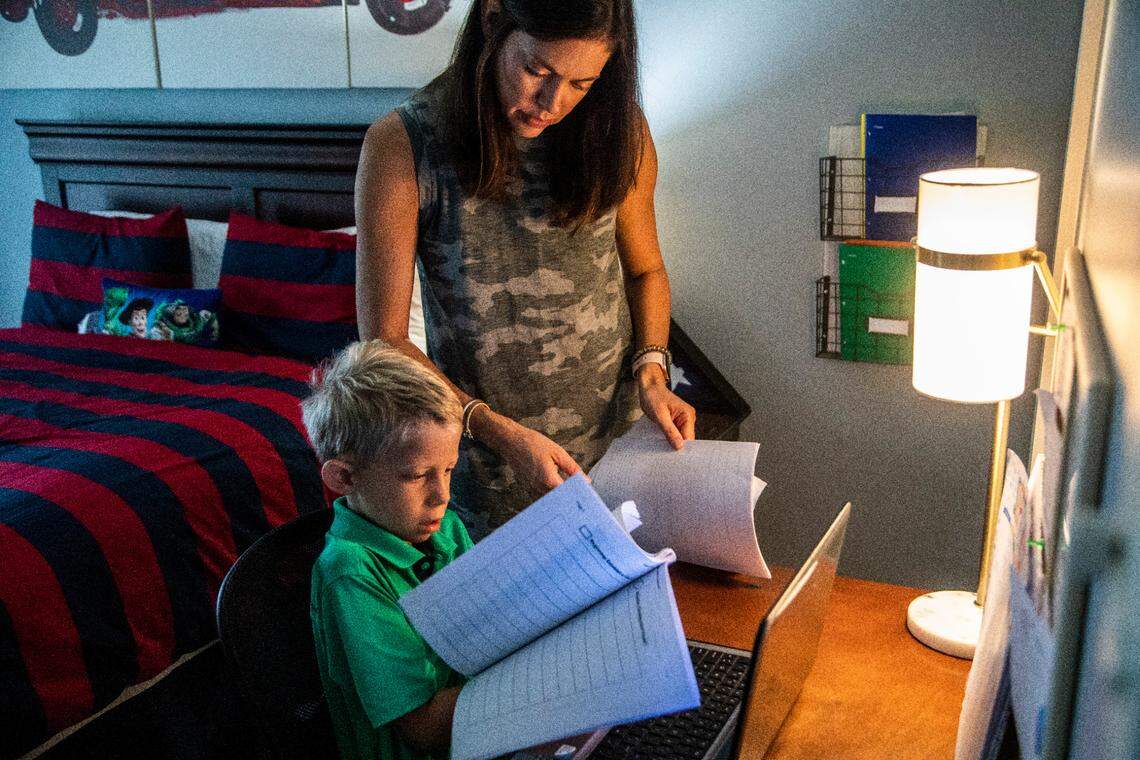 Erin Wall helps her son Carter, a second-grader Penny Road Elementary prepare for a remote learning lesson Wednesday, Sept. 9, 2020 at their home in Cary. Wall says her son who has would benefit more in a classroom setting.