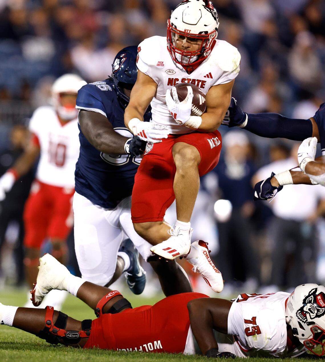 N.C. State running back Jordan Houston (3) leaps over offensive lineman Anthony Carter Jr. (75) as he gains yards during the second half of N.C. State’s 24-14 victory over UConn at Rentschler Field in East Hartford, Conn. Thursday, August 31, 2023.