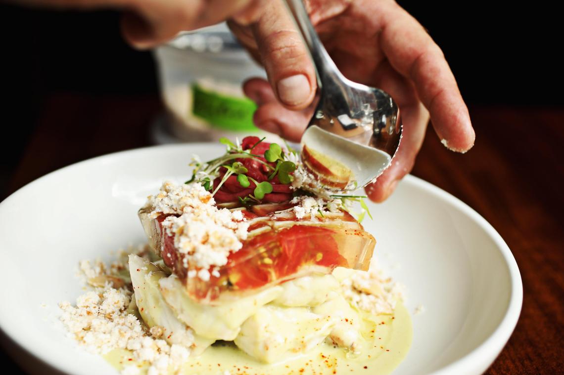 Executive chef Todd Woods plates the heirloom tomato gazpacho terrine at Oak Steakhouse in downtown Raleigh. The dish is made up of thin slices of ripe tomato set like so many jewels in a block of sparkling clear aspic and set on a canvas of white gazpacho and colossal lump crabmeat.