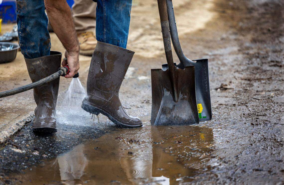 A volunteer working to clean the interior of the flooded historic Gentry Hardware, washes the muck off their boots and shovels on Friday, October 4, 2024 in Hot Springs, N.C.