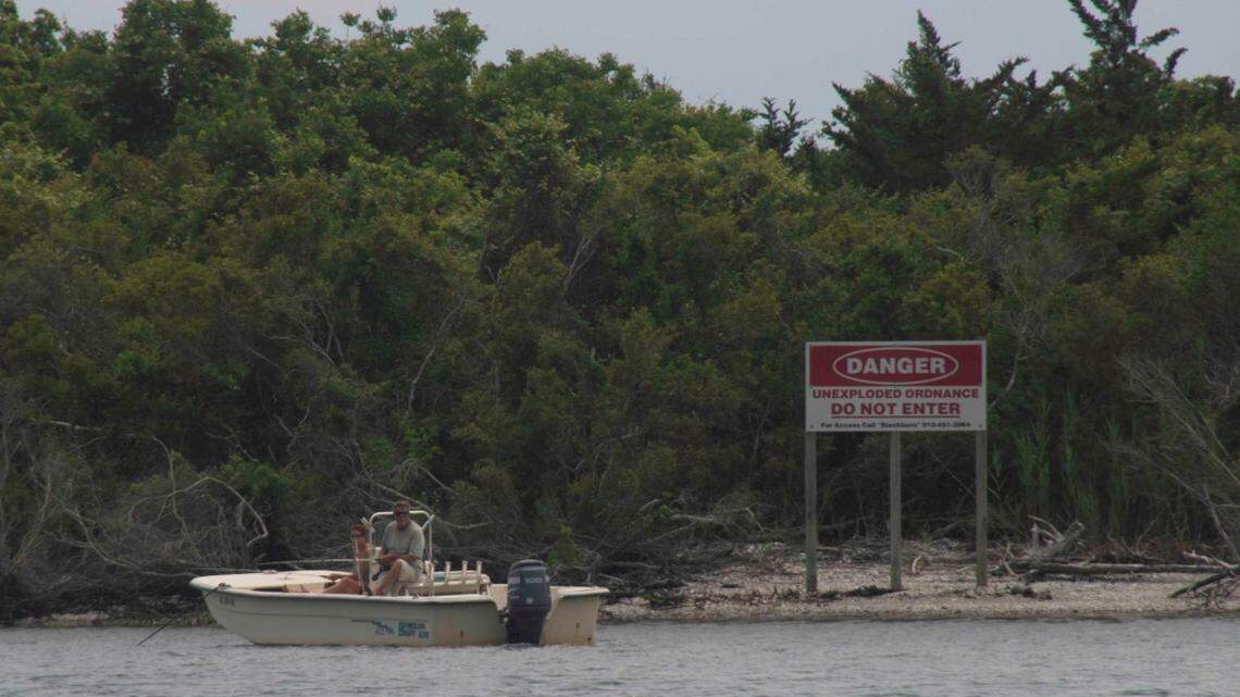A couple sits “illegally anchored” near Brown’s Island in the Atlantic‐Intracoastal Waterway. The island is dangerous and off limits to the public due to unexploded bombs.