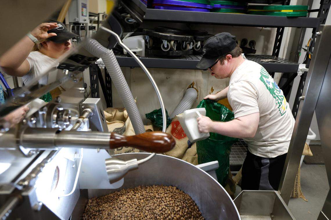 Paul Kocher measures 26 lbs. of coffee beans from Peru to be roasted at the 321 Coffee roasting facility in Raleigh, N.C., Tuesday, June 25, 2024. Reflected to the left is Sophie Pacyna.