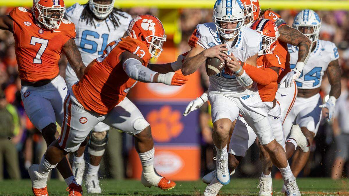 Clemson’s Tyler Davis (13) and Andrew Mukuba (1) stop North Carolina quarterback Drake Maye after a five-yard gain in the first quarter on Saturday, November 18, 2023 at Memorial Stadium in Clemson, S.C.