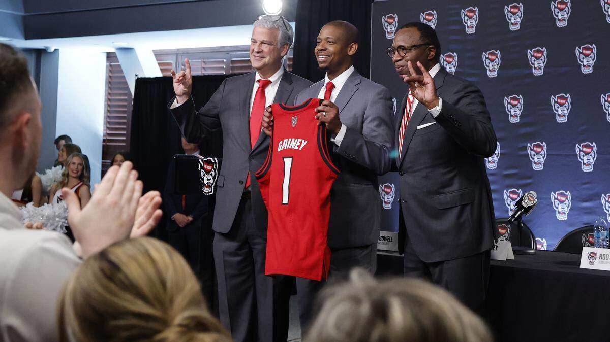 New N.C. State head men’s basketball coach Justin Gainey is flanked by Athletic Director Boo Corrigan and Chancellor Kevin Howell after Gainey was introduced during press conference at the Lenovo Center in Raleigh, N.C.,  Wednesday, April 1, 2026.