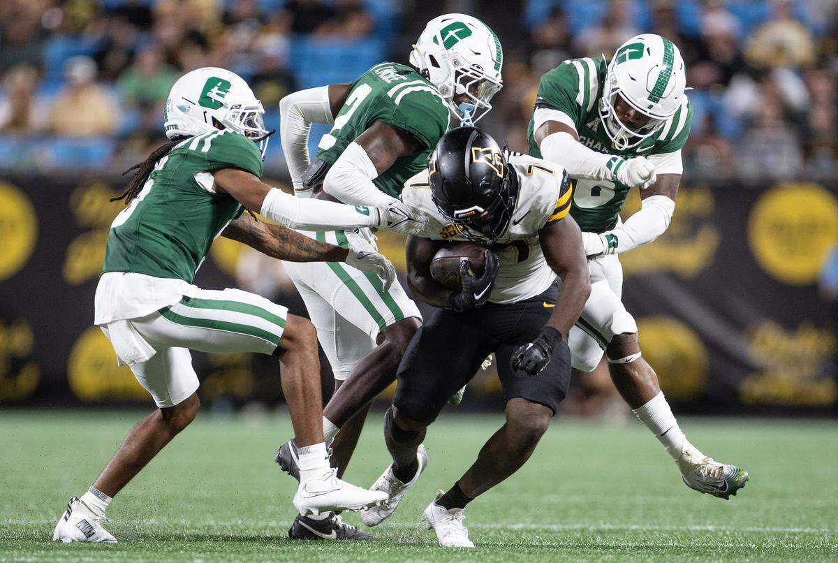 Appalachian State Mountaineers running back Rashod Dubinion, center, is tackled by a host of Charlotte 49ers defenders during the Duke's Mayo Classic at the Bank of America Stadium in Charlotte, N.C., on Friday, August 29, 2025.