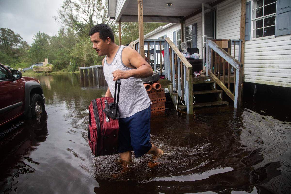 Chavez Gallegos, 24, helps his family move  out of a flooded home on Will Baker Road in Kinston Sunday, Sept. 16, 2018, following the aftermath of Hurricane Florence. 