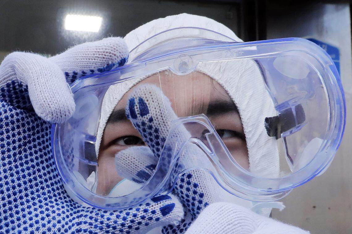 A worker cleans his goggles to spray disinfectant as a precaution against the coronavirus at a shopping street in Seoul, South Korea, Thursday, Feb. 27, 2020. South Korea and China each reported hundreds more virus cases Thursday as the new illness persists in the worst-hit areas and spreads beyond borders.