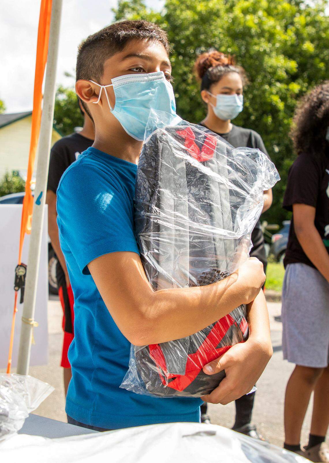 Brian Barajas picks up a backpack, school supplies, and lunch from the Durham Rescue Mission during its annual Back-To-School Pep Rally that was modified to be a drive-through event this year to reduce contact amid rising cases of COVID-19, on Wednesday, Aug. 18, 2021, in Durham, N.C.