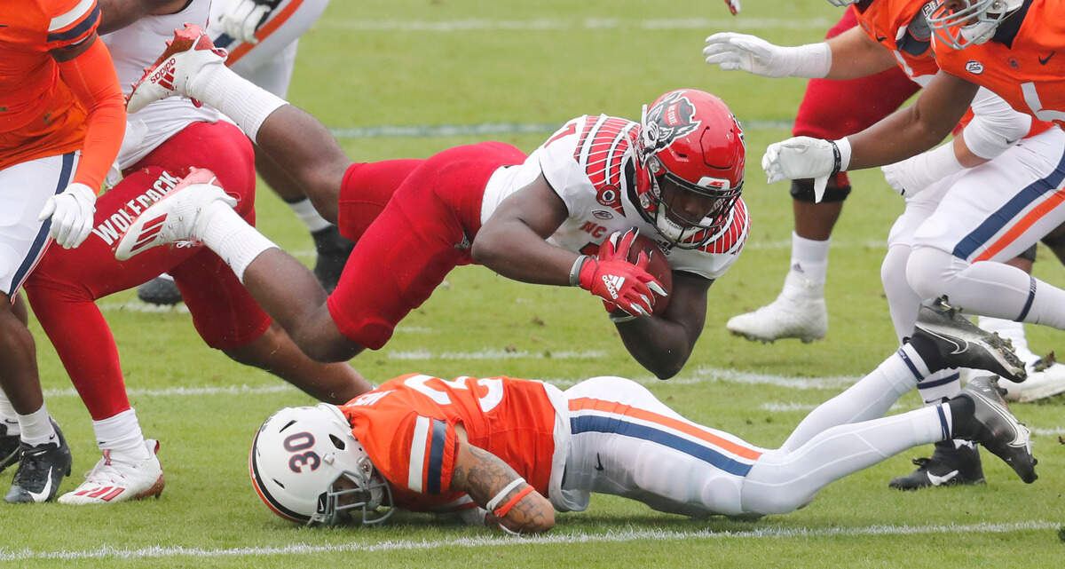 Virginia safety D’Angelo Amos (30) trips up N.C. State running back Zonovan Knight (7) during the first half of N.C. State’s game against Virginia at Scott Stadium in Charlottesville, Va., Saturday, Oct. 10, 2020.