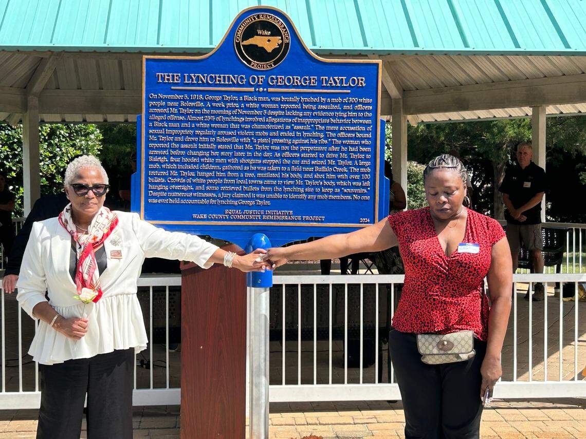 Sharin Wilson of New York holds hands with Kimberly McDowell-Lois of New Jersey as a marker to their ancestor George Taylor’s lynching is unveiled in Rolesville.