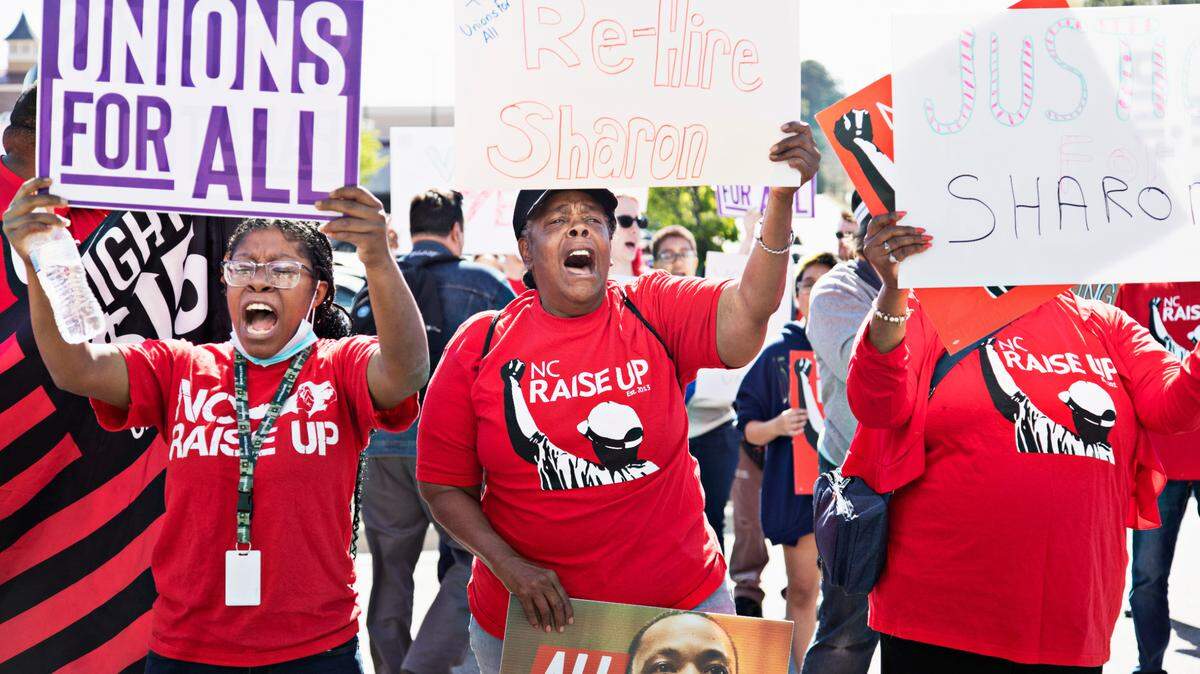 Eshawney Gaston, left, and Mama Cookie, center, with Fight for $15, protest outside of the at the Wake Forest & Six Forks Starbucks in Raleigh on April 11, 2022, in response to the firing of vocal union leader Sharon Gilman earlier this month.
