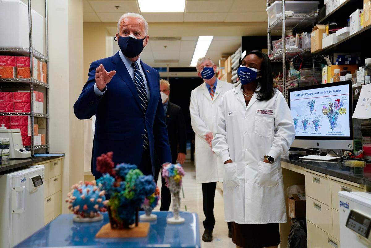 President Joe Biden speaks as he visits the Viral Pathogenesis Laboratory at the National Institutes of Health, Thursday, Feb. 11, 2021, in Bethesda, Md. Francis Collins, National Institutes of Health Director and Kizzmekia Corbett, right, listen.