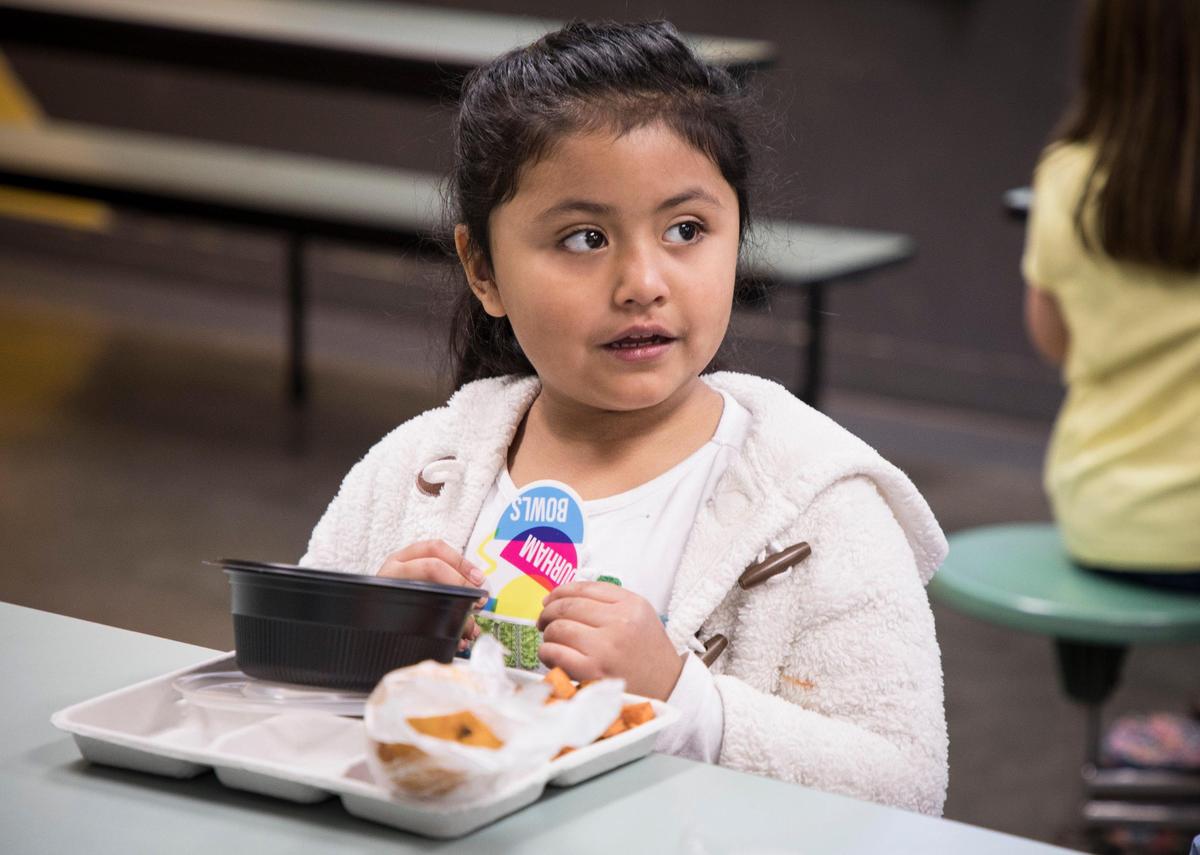 Alexa Reyes-Garcia, 5, holds a “Durham Bowls” sticker she received with her Cuban pork and rice bowl, a new lunch menu item at George Watts Elementary School, on Thursday, Jan. 24, 2019.
