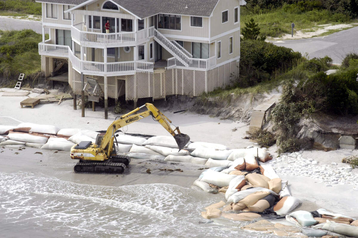 An excavator moves car-size sandbags into place in an attempt in 2005 to protect houses on Figure Eight Island from the pounding surf.