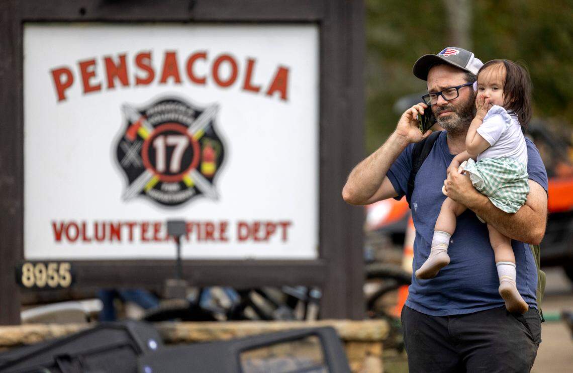 Henri McGowan, who lives in the village of Pensacola, in Yancey County, N.C. holds his daughter Violet as he calls loved ones using the Starlink Internet service at the community fire department on Thursday, October 3, 2024 in Pensacola, N.C.